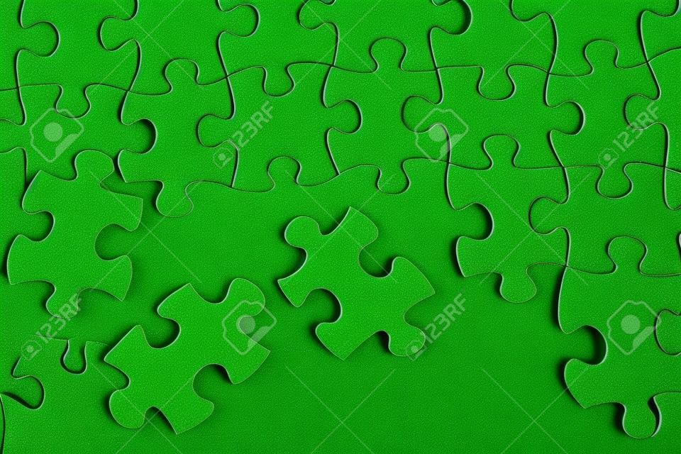 Puzzle pieces on green background close up. 