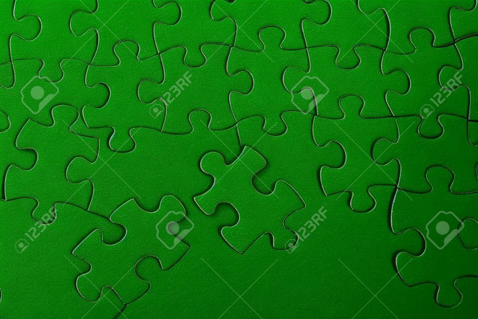 Puzzle pieces on green background close up. 