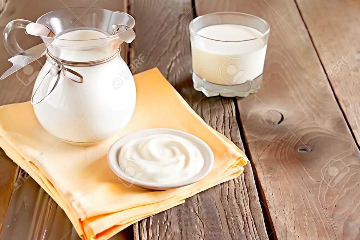Calcium zuivel verse producten: melk en zure room (yoghurt) op servet en houten tafel, close-up, horizontal, kopieerruimte