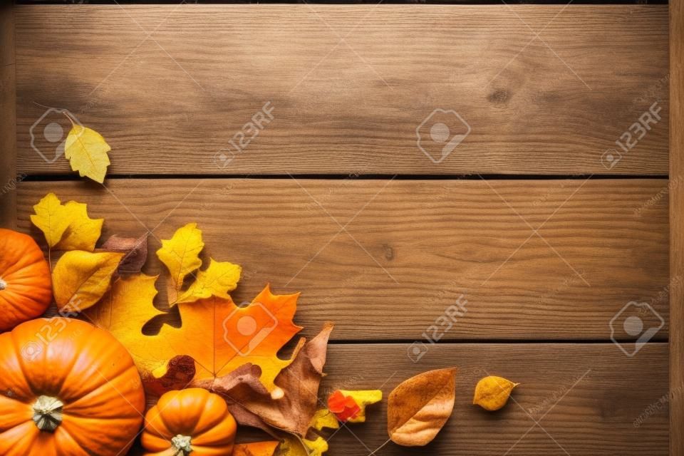 Thanksgiving or Autumnal holiday background, top view, copy space. Autumnal holiday composition with pumpkins, nuts, yellow leaves.