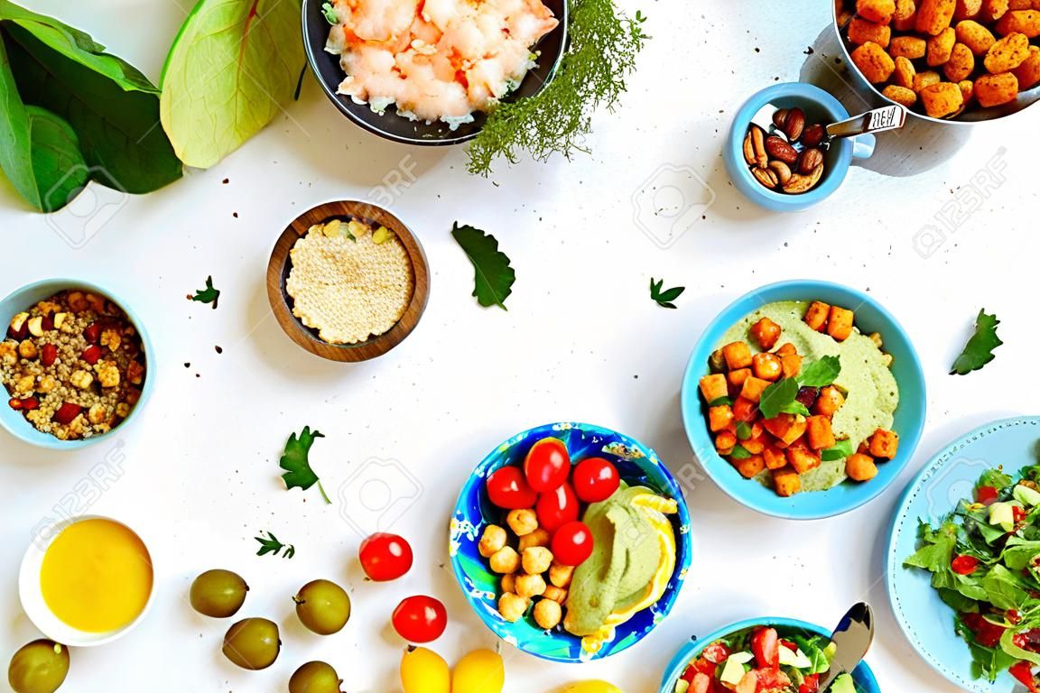 Vegan dinner table, set of healthy vegan vegetarian dishes for lunch - quinoa and chickpea salad, fried tofu, hummus dip, fruits, vegetables, nuts, seeds, top view, copy space, flat lay.