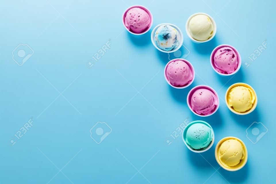 Eis-Sortiment. Verschiedene Eiscremes oder Gelato auf blauem Hintergrund, Kopienraum. Gefrorener Joghurt in kleinen Bechern - gesundes Sommerdessert.