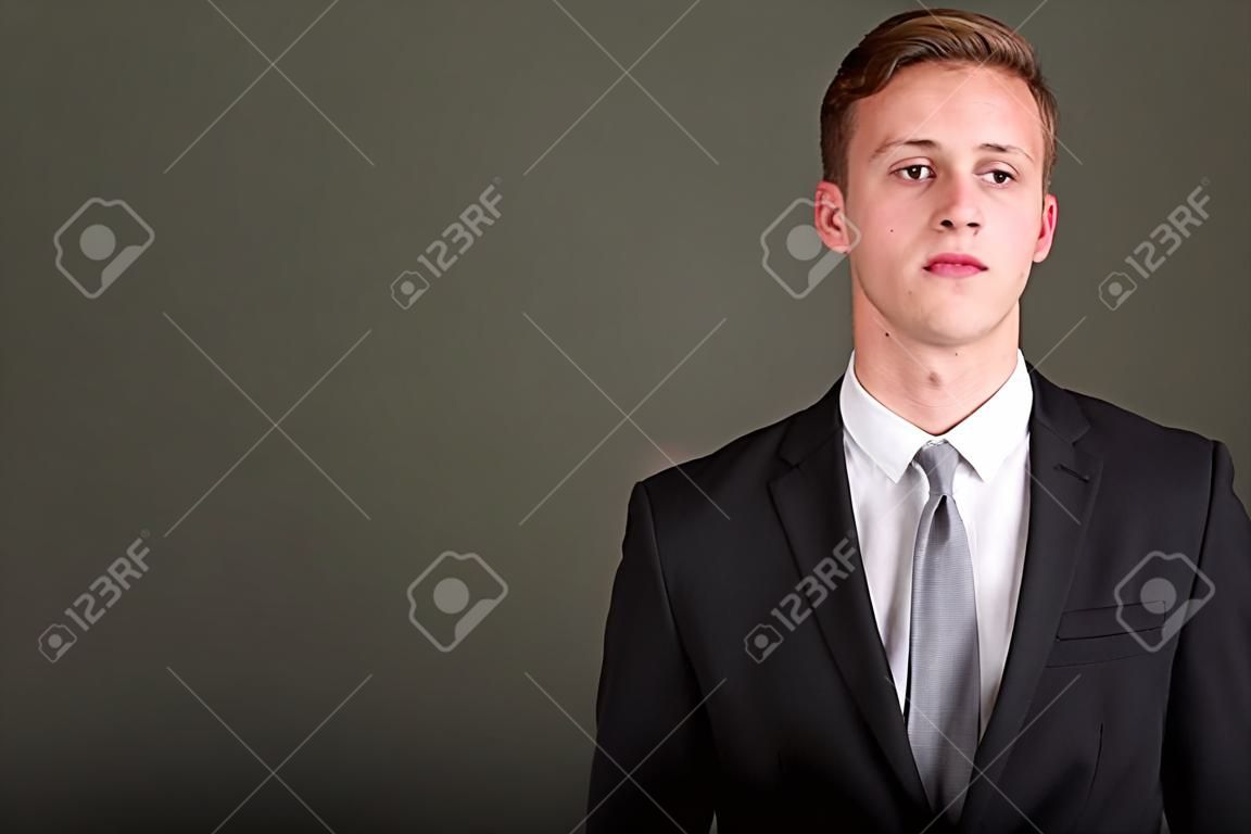 Young handsome businessman wearing suit against colored backgrou