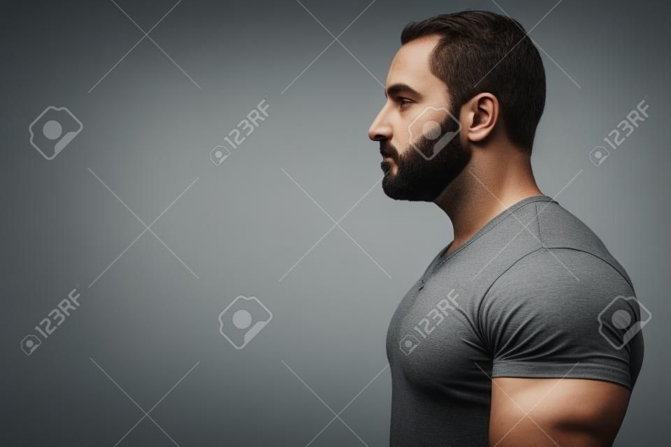 Profile view of muscular bearded man wearing gray shirt