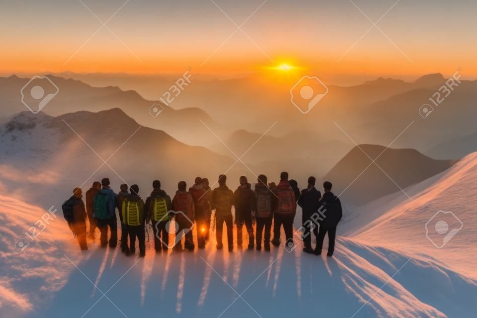 Gruppo di persone in piedi sulla cima di una montagna e guardando il tramonto
