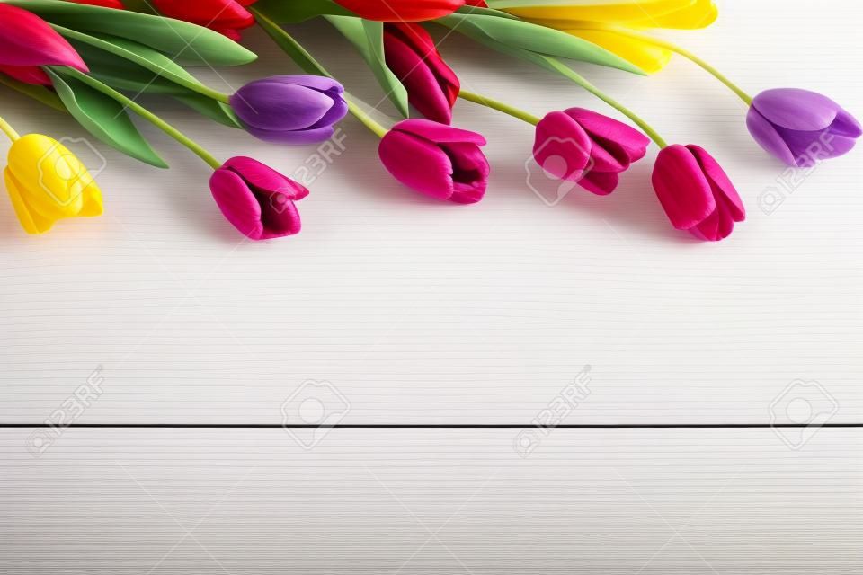 Tulipes colorées sur une table en bois blanche avec espace copie