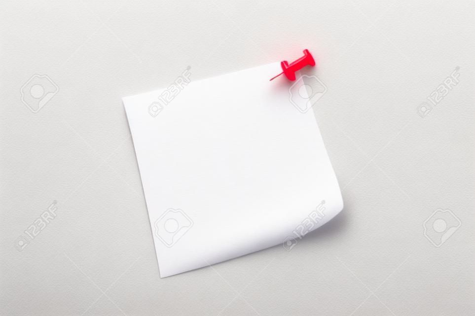 Close-up lege papieren notitie op witte achtergrond en rode pinnen.