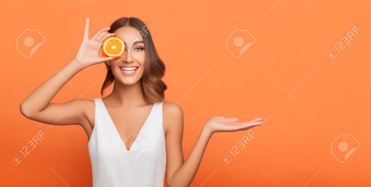 Mooie glimlachende vrouw met oranje. Mooi meisje model met natuurlijke make-up, gloeiende gezichtshuid en citrusvruchten. Vitamine C cosmetica concept
