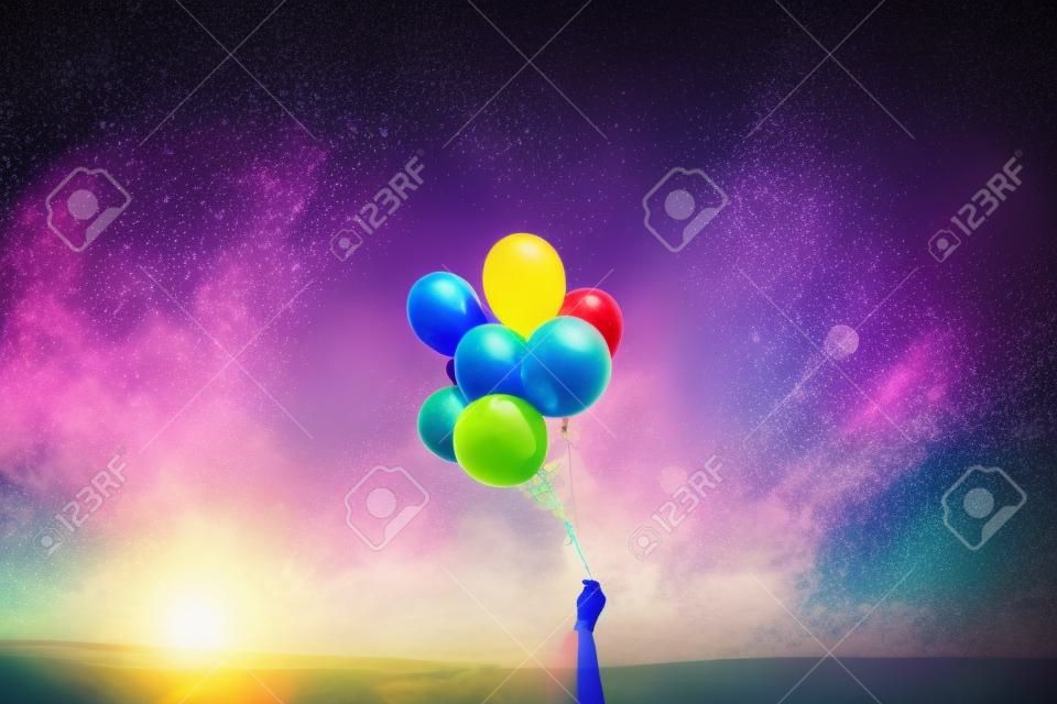 hand holding colorful balloons on a background of nature