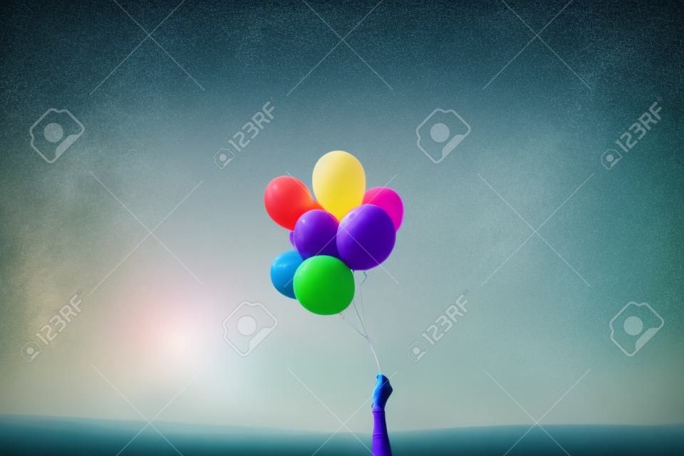 hand holding colorful balloons on a background of nature