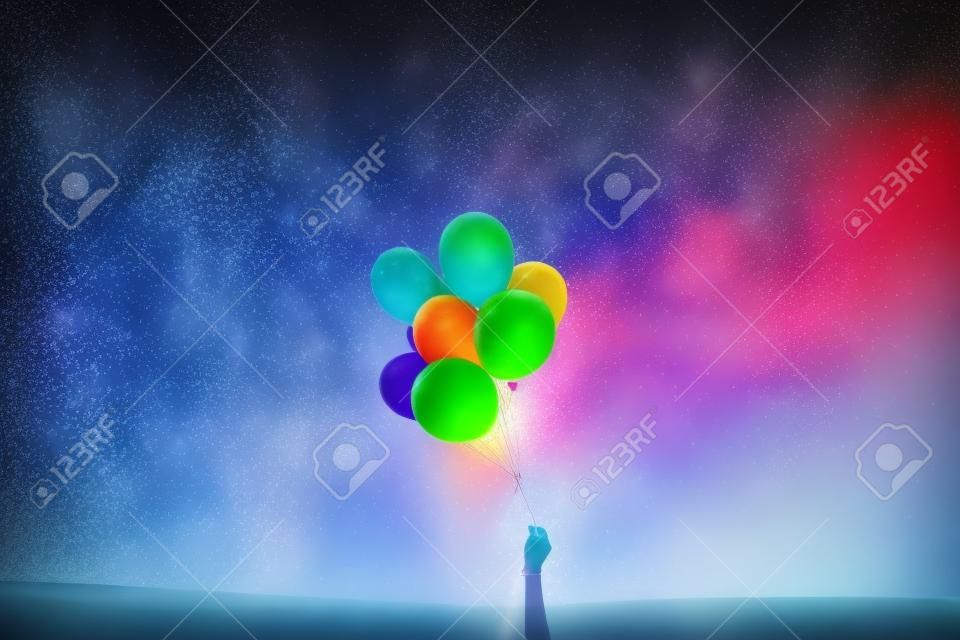 mão segurando balões coloridos em um fundo da natureza