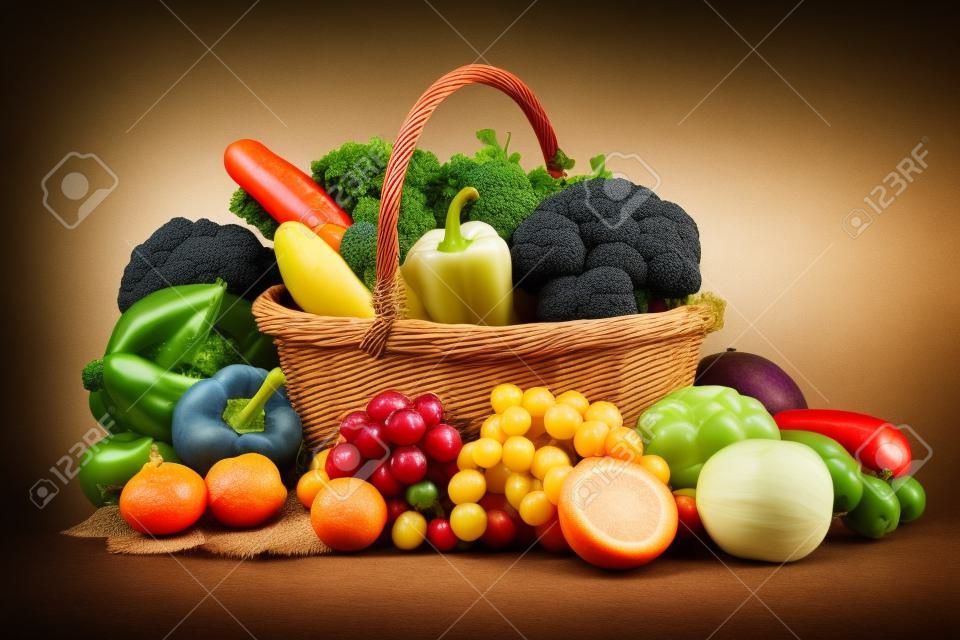 Composición con verduras y frutas en canasta de mimbre aislado en blanco