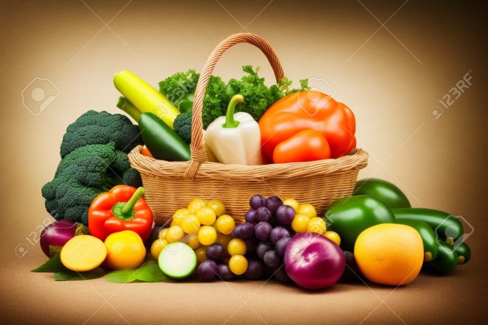 Composition avec des légumes et des fruits dans le panier en osier isolé sur blanc