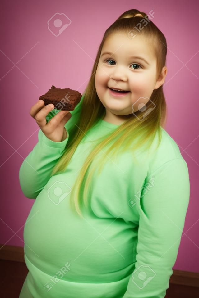 Overweight girl holding brownie, portrait