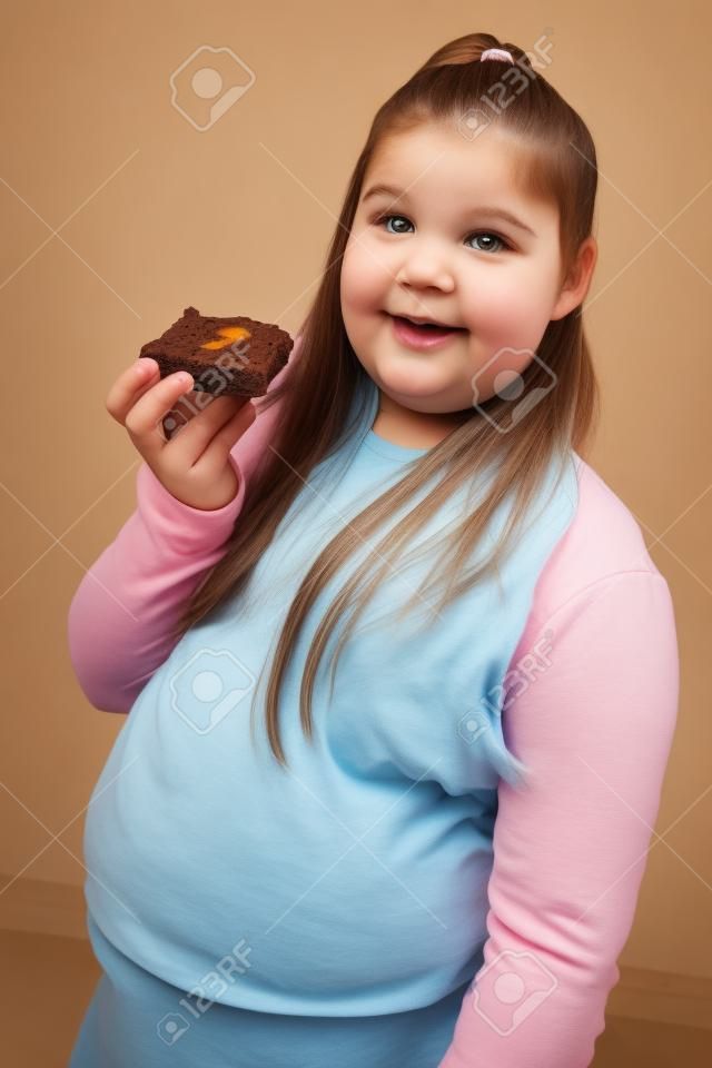 Overweight girl holding brownie, portrait