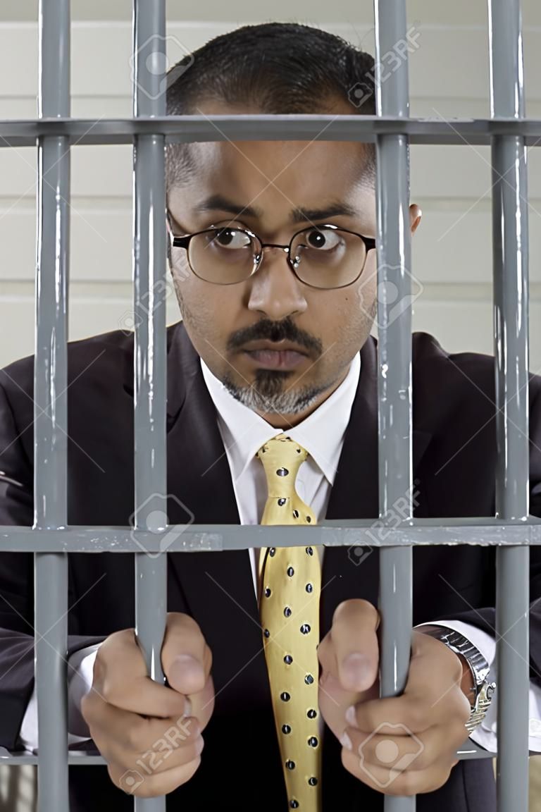 Homme d'affaires debout derrière les barreaux des cellules de prison