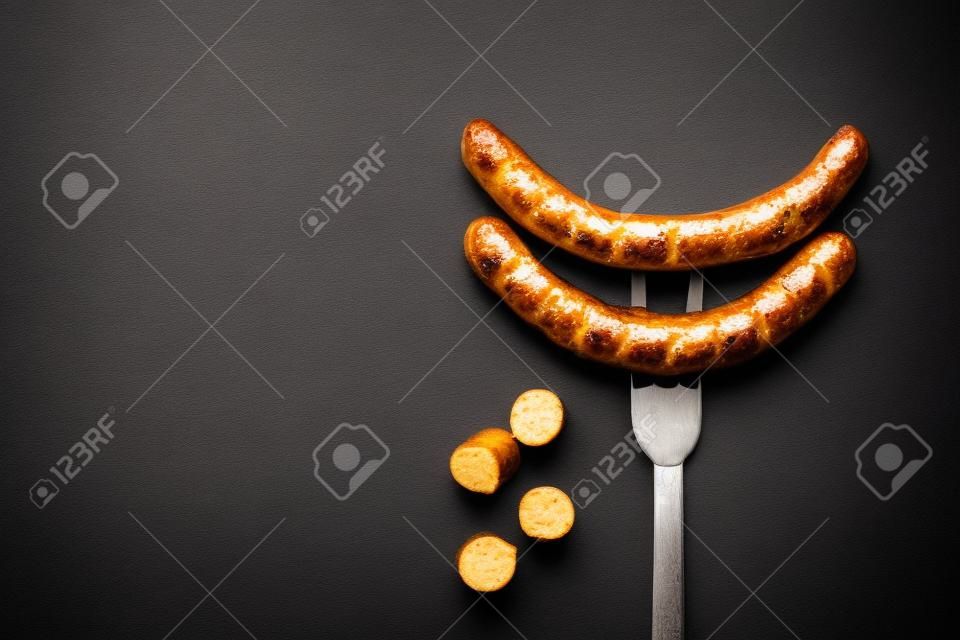 Fried sausage on a fork impaled on a background