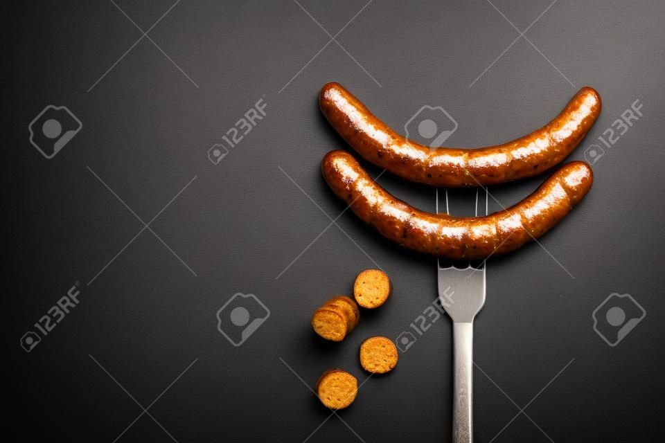 Fried sausage on a fork impaled on a background