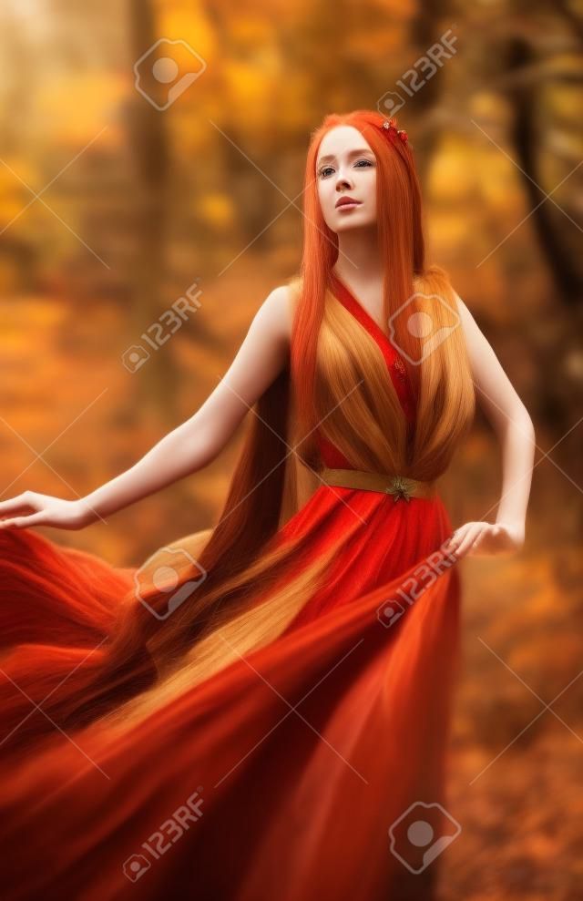 A beautiful long-Haired red-haired elf girl stands in the wind in the autumn forest. A fairy woman with long hair in a fairy dress.