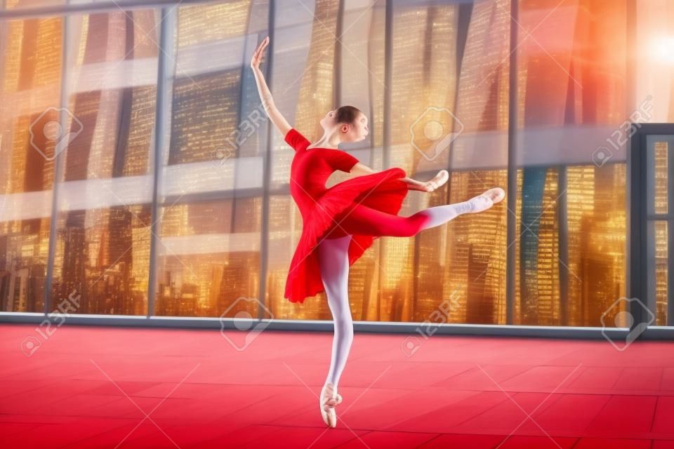 Eine junge Ballerina in einem knallroten Tutu tanzt vor dem Hintergrund einer Stadtlandschaft