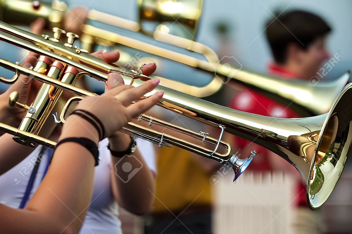 Trombone players with hands on the main slide for the marching band.