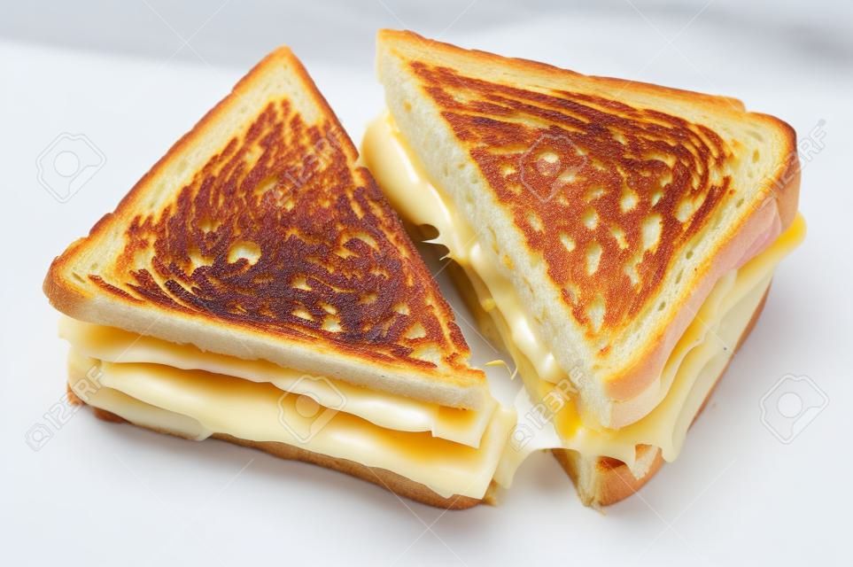 Sandwich grillé classique au fromage et au jambon coupé en deux isolé sur blanc.