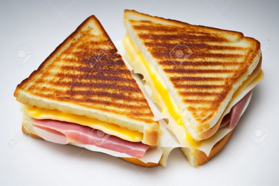 Sandwich grillé classique au fromage et au jambon coupé en deux isolé sur blanc.