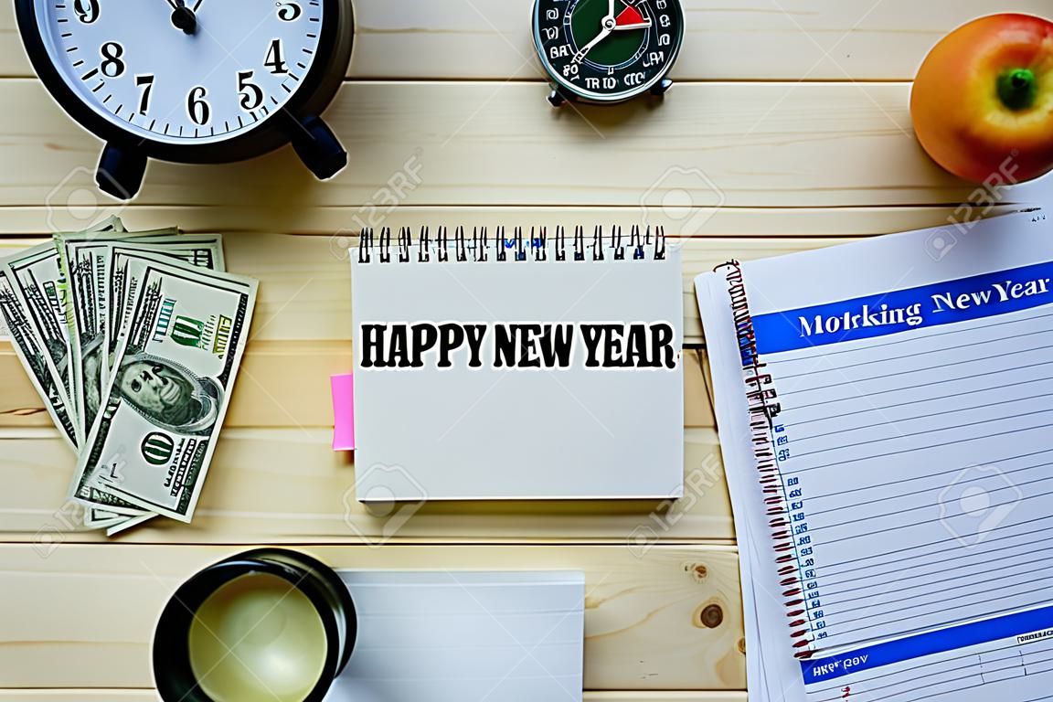 Top view conceptual image of working table. Words HAPPY NEW YEAR on notepad.