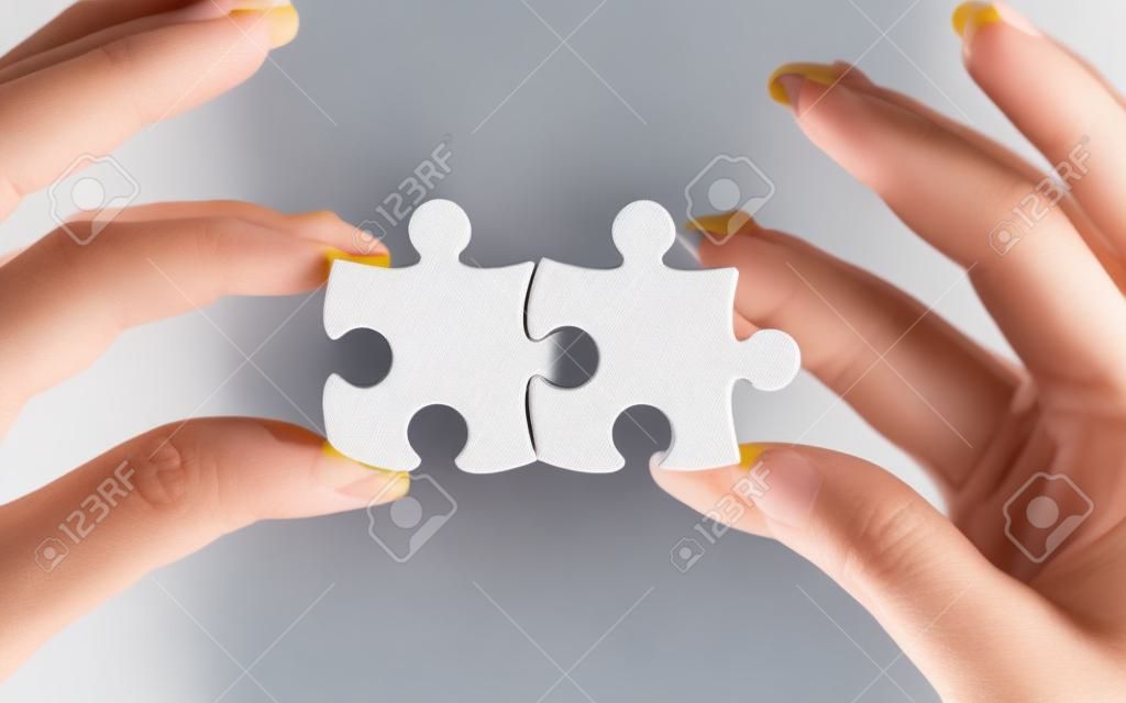 Woman holding two puzzle pieces in hands. Good for business concept.