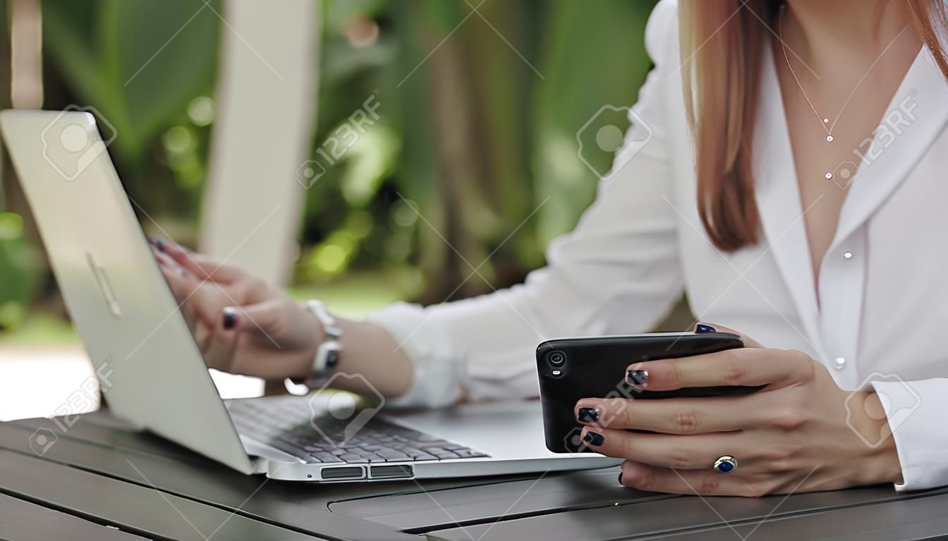 Lady business utilizzando un computer portatile e un telefono. Colpo di Close-up. Focalizzazione morbida