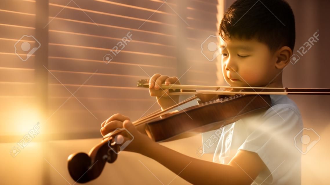 朝日光を浴びてバイオリンを弾くアジアの少年。の写真素材・画像素材