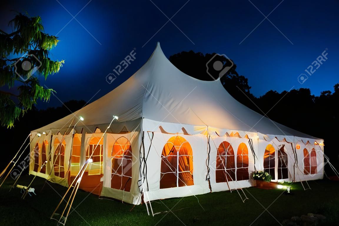 Een bruiloft tent's nachts met blauwe hemel en de maan. De muren zijn naar beneden en de tent is opgezet op een gazon - bruiloft tent serie