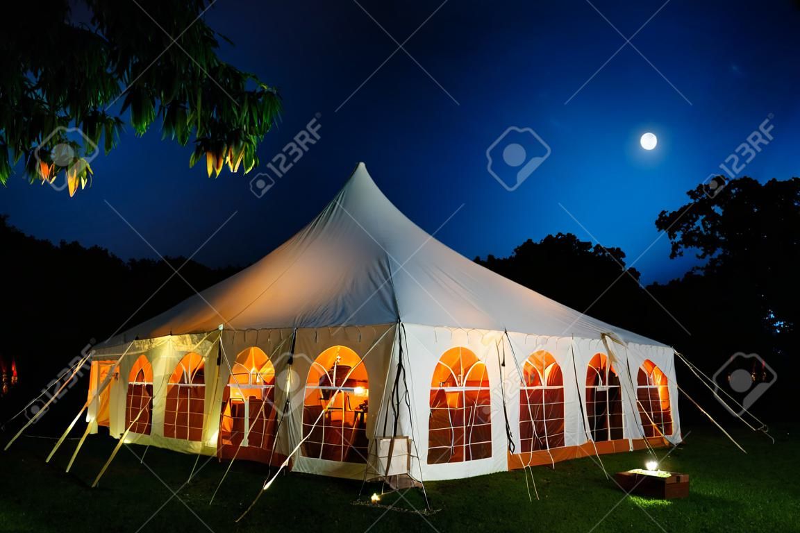 Namiot ślubny w nocy z błękitnym niebem i księżycem. Ściany opuszczone, namiot rozstawiony na trawniku - seria namiot ślubny