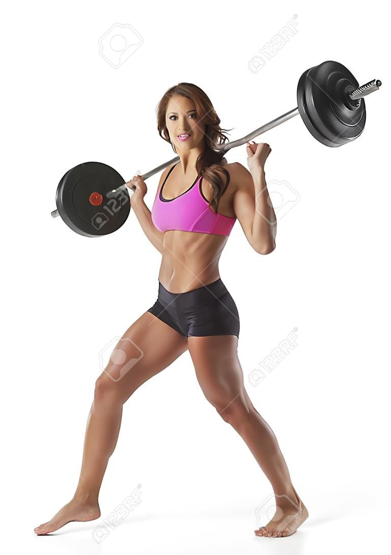 Attractive young woman standing with barbell on shoulders against white background.