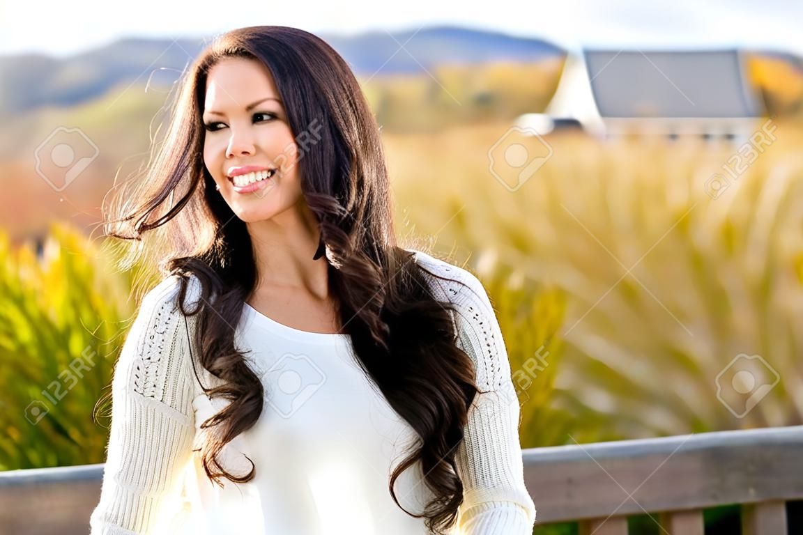 Smiling, pretty brunette on Fall nature walk with tall grass and lake in background
