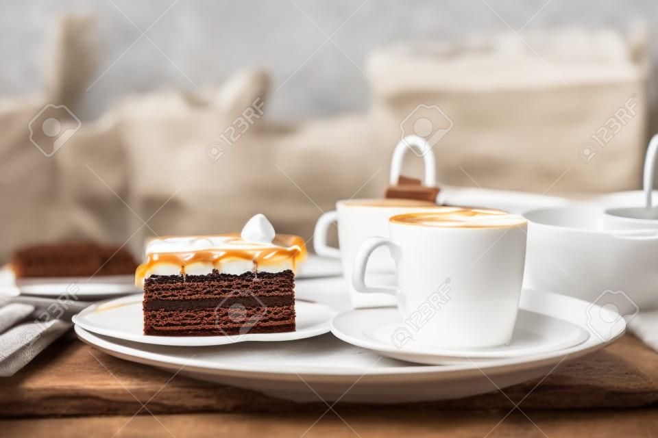cup of a fresh caramel latte with whipped cream on the table and chocolate cake.
