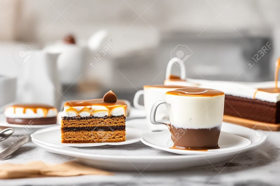 cup of a fresh caramel latte with whipped cream on the table and chocolate cake.
