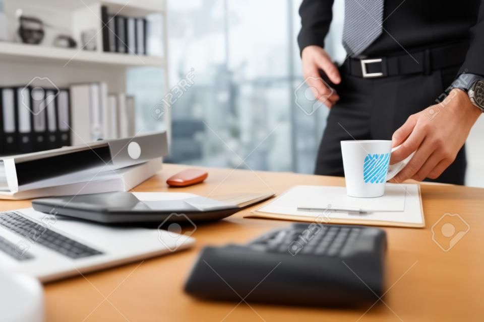 Buchhalter steht und hält eine Kaffeetasse und arbeitet an Unternehmensdaten, dokumentiert und berichtet über das Schreibtischbüro. Buchhaltung Geschäftskonzept.