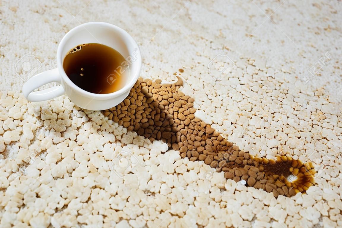 Une tasse de café est tombée sur un tapis. La tache est au sol.