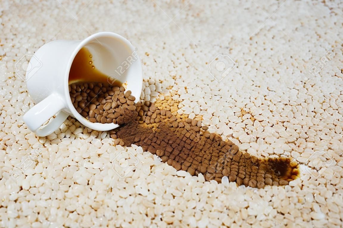 Une tasse de café est tombée sur un tapis. La tache est au sol.