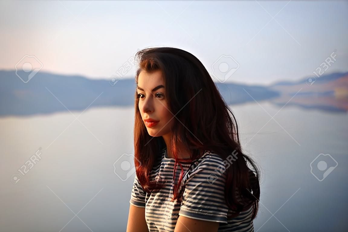 Girl on the background of the lake. Sunset or sunrise.