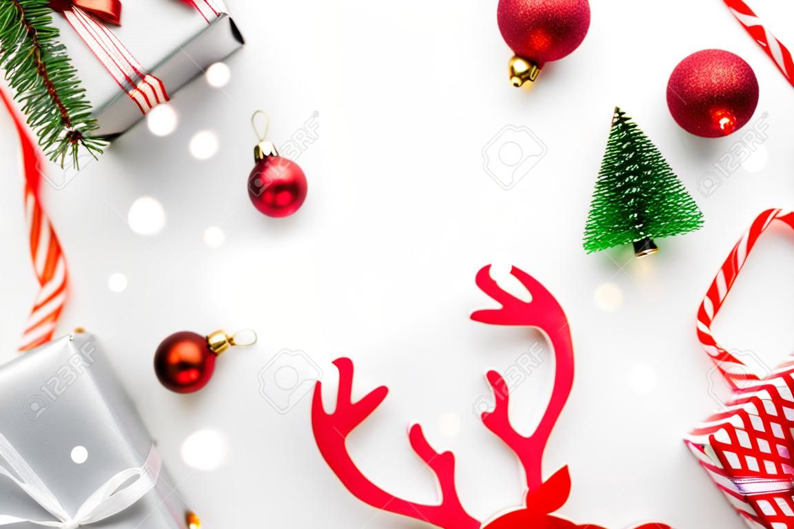 Christmas background. White gifts with scarlet bow, red balls and sparkling lights in xmas decoration on white background for greeting card. Decoration and copy space for your text