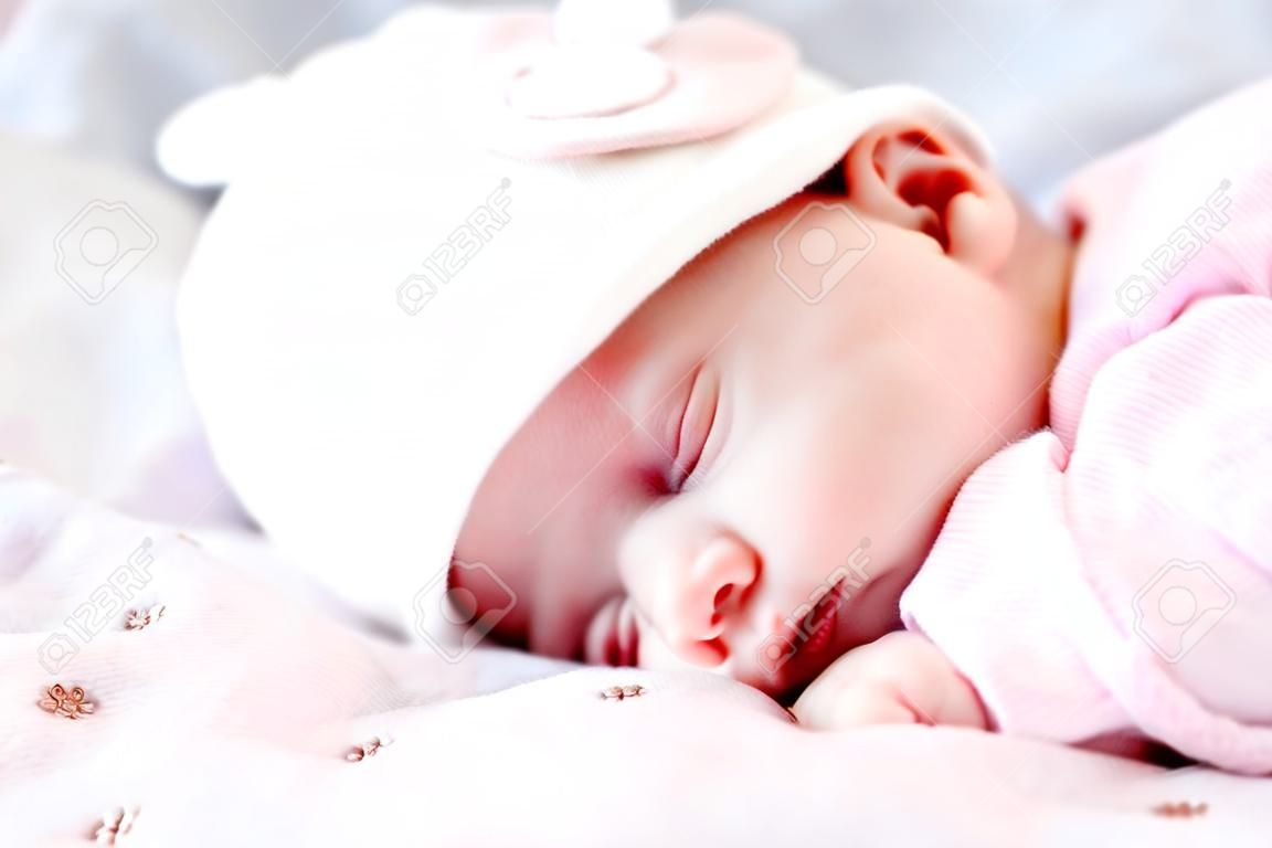 Enfance, soins, maternité, concepts de santé - gros plan petite paix calme nouveau-né fille au chapeau rose dort au repos faire une sieste profonde allongée sur le ventre sur une couverture douce et chaude pilow nid avec les yeux fermés