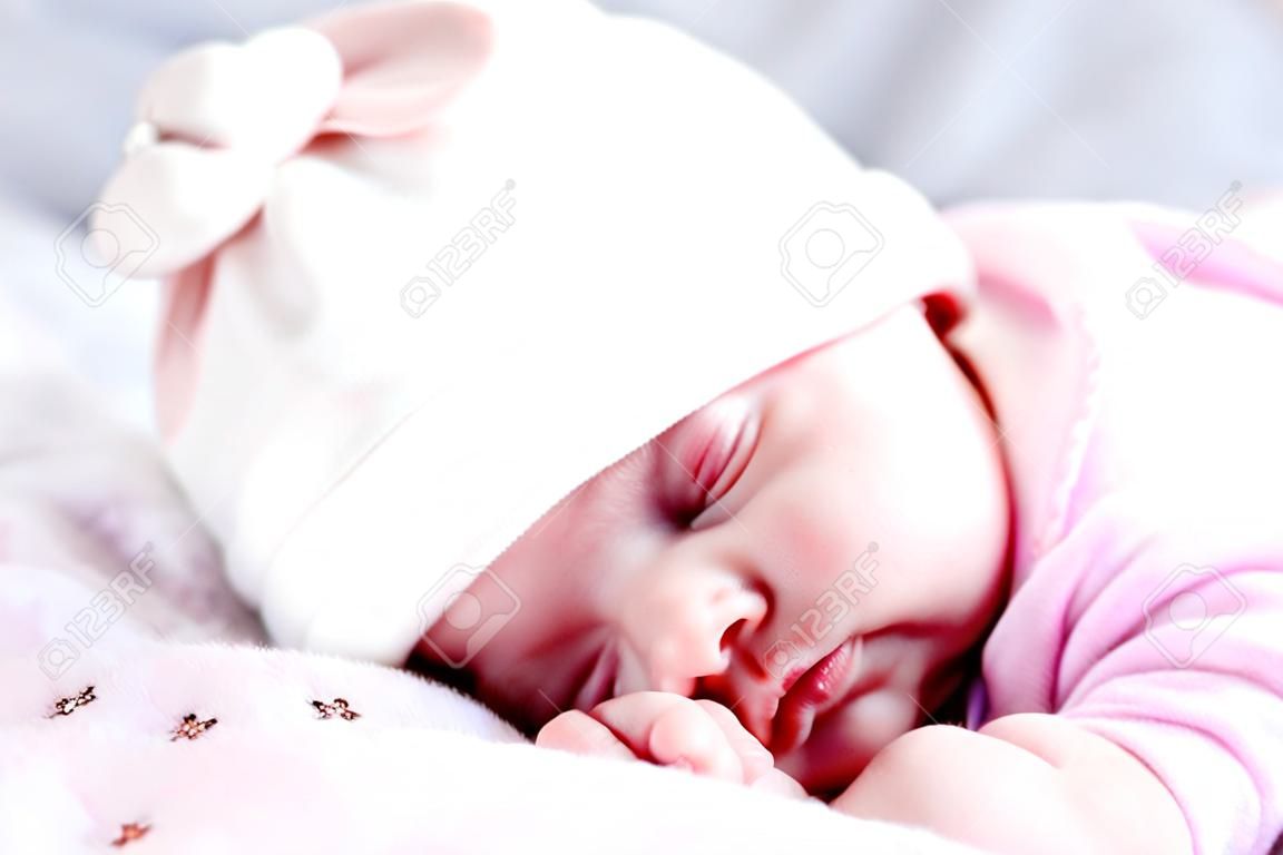 Childhood, care, motherhood, health concepts - Close up Little peace calm newborn baby girl in pink hat sleeps resting take deep nap laying on tummy on soft warm blanket pilow nest with close eyes
