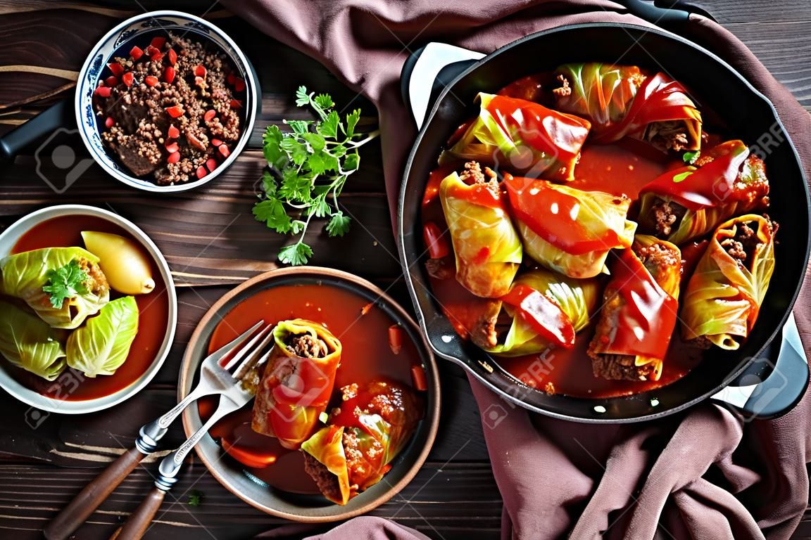 cabbage rolls stuffed with ground beef and rice and cooked to perfection with a tangy tomato sauce in a dutch oven and served on a plate with cutlery, view from above, close-up, flatlay