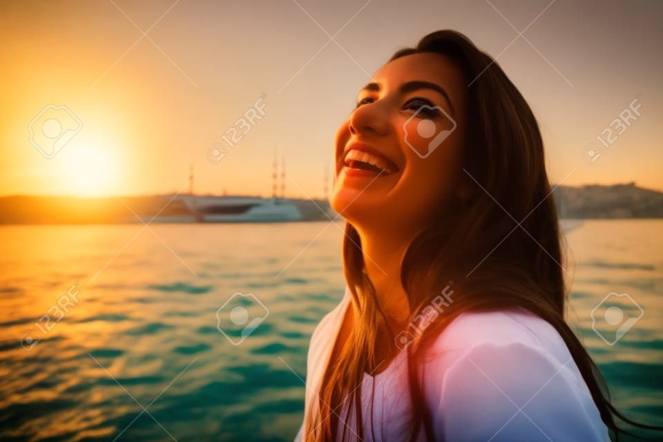 Portret van een mooie latin meisje op een jacht bij zonsondergang en lacht, een veerboot reis, luxe Istanbul reizen