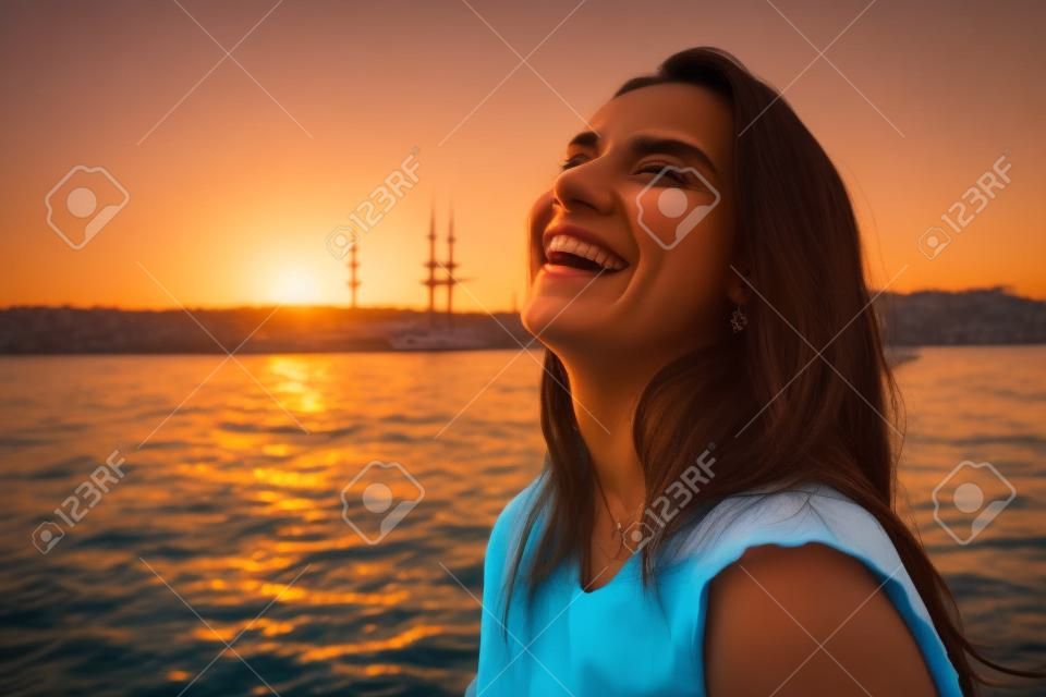 Portret van een mooie latin meisje op een jacht bij zonsondergang en lacht, een veerboot reis, luxe Istanbul reizen