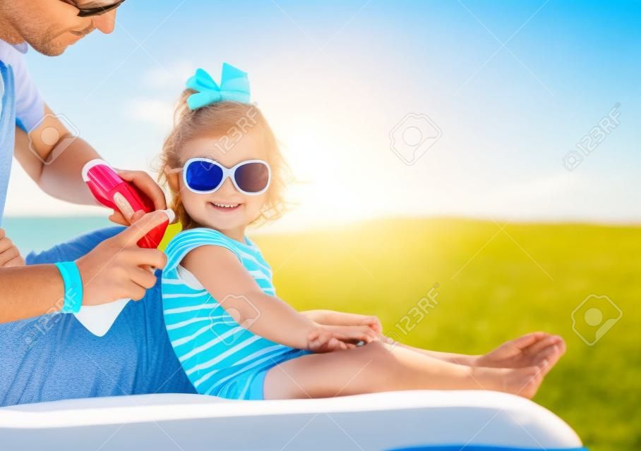 padre de aplicar la crema protector solar en el hombro hijas, la protección del sol