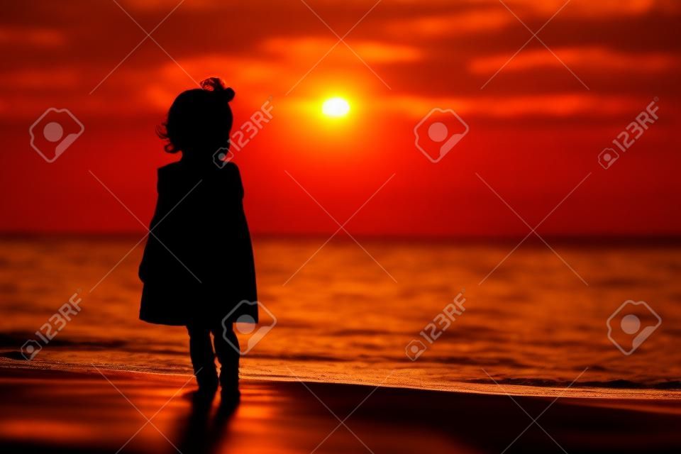 silhouette de petite fille qui marche au coucher du soleil plage