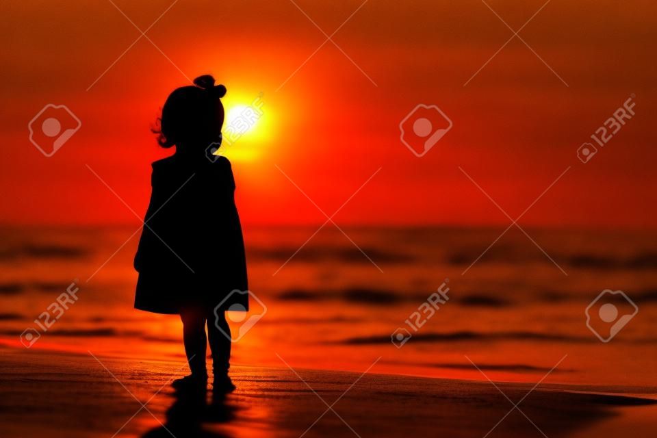silhouette de petite fille qui marche au coucher du soleil plage